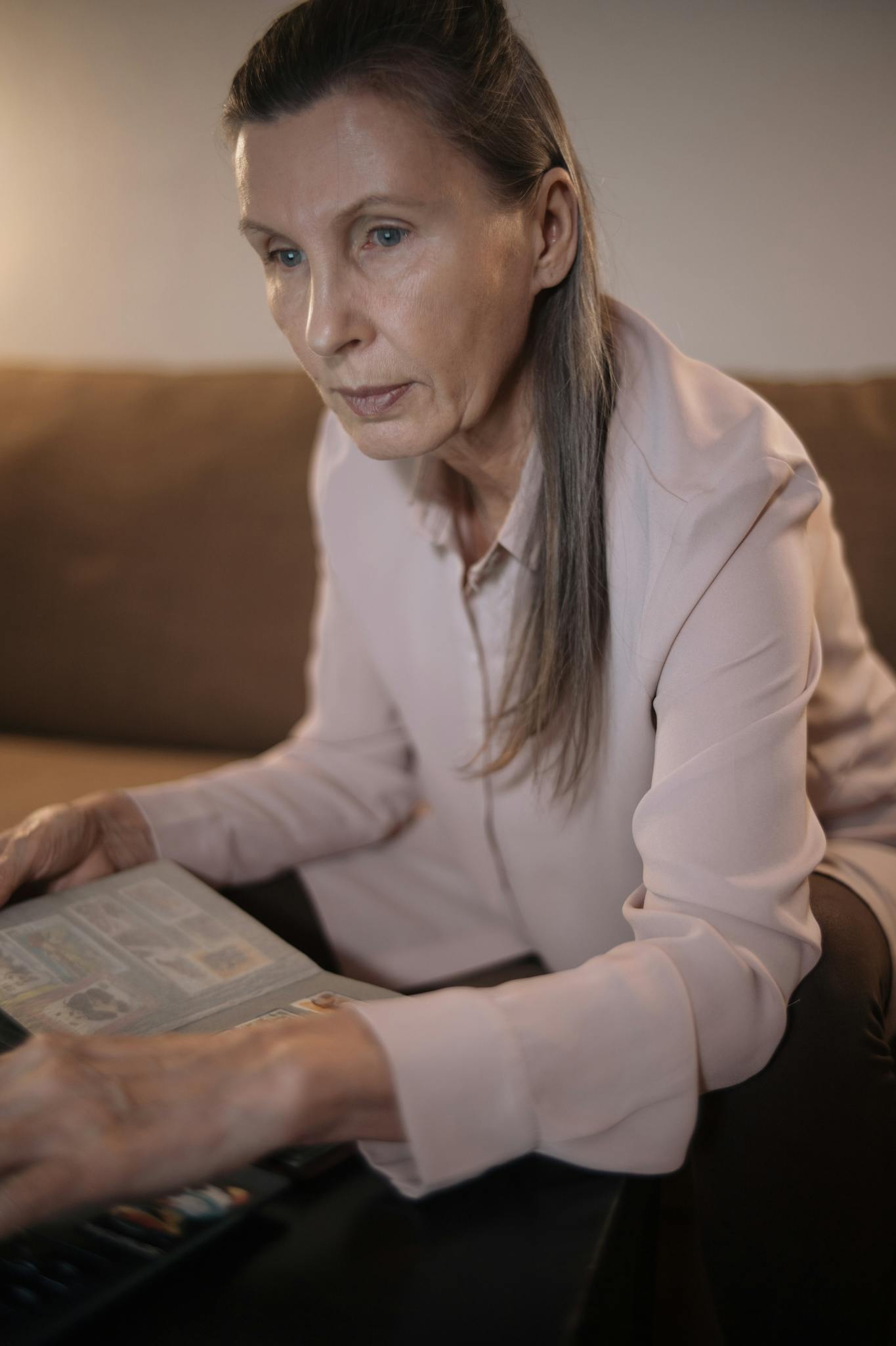 Elderly woman engaging with technology at home, focused and thoughtful.